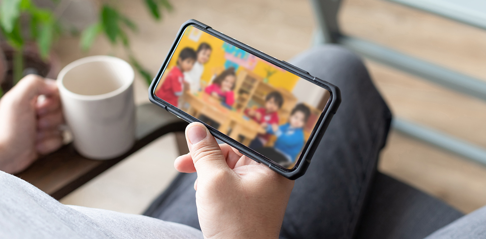 person hand holding smartphone with multiple camera views of office locations. Surveillance, modern technology blurred background