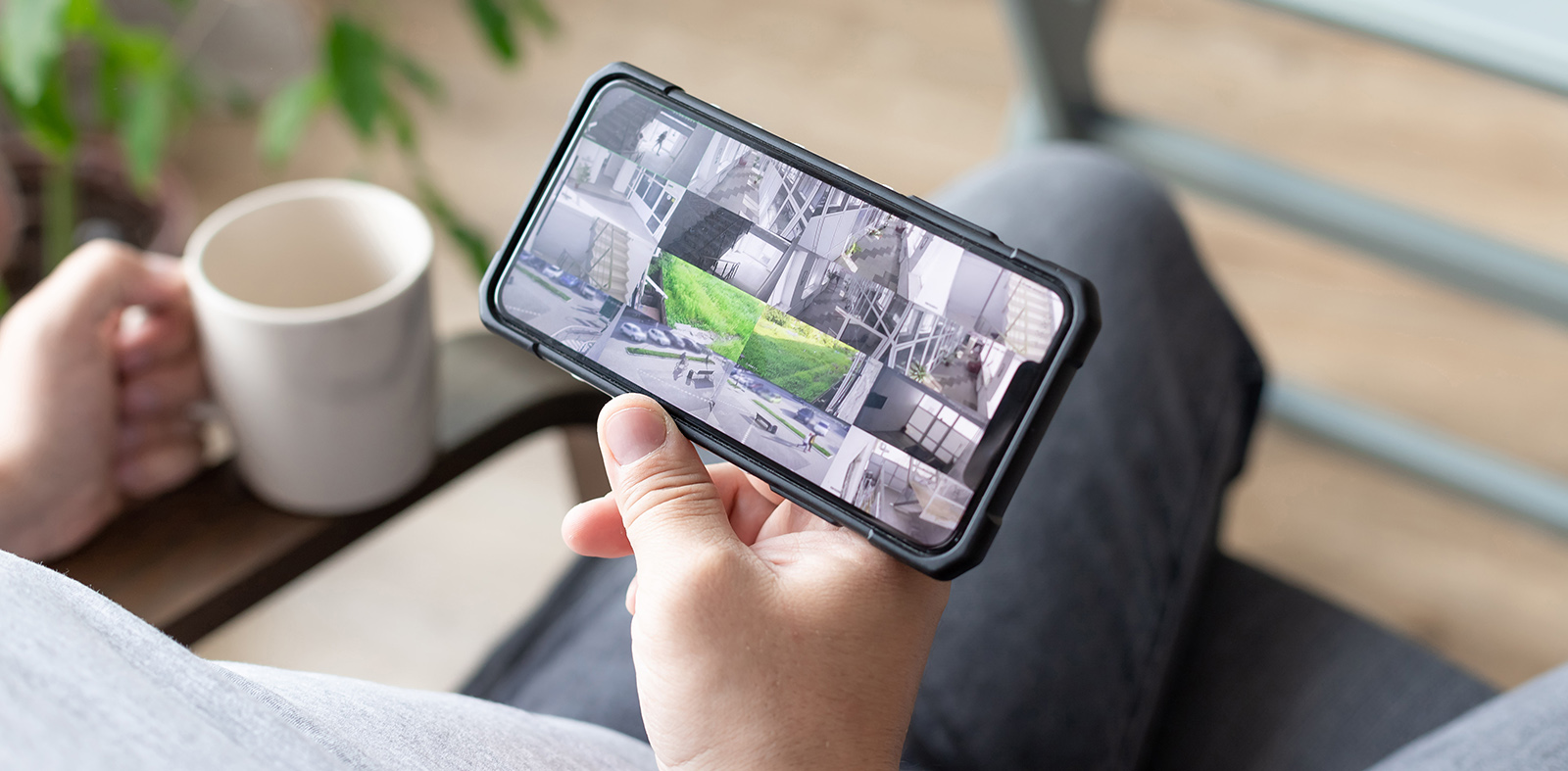 person hand holding smartphone with multiple camera views of office locations. Surveillance, modern technology blurred background